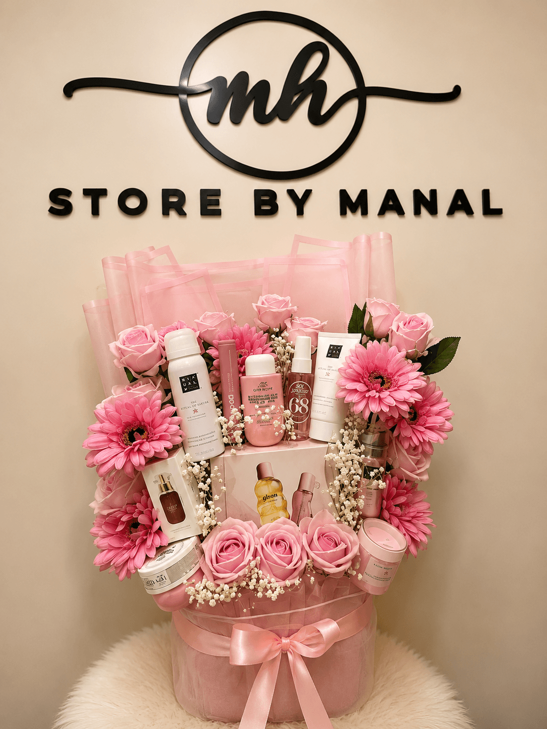 Composition cadeau rose réunissant soins, parfums et fleurs devant l’enseigne Store By Manal